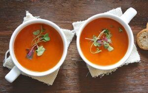 pots of soup with herb garnishes